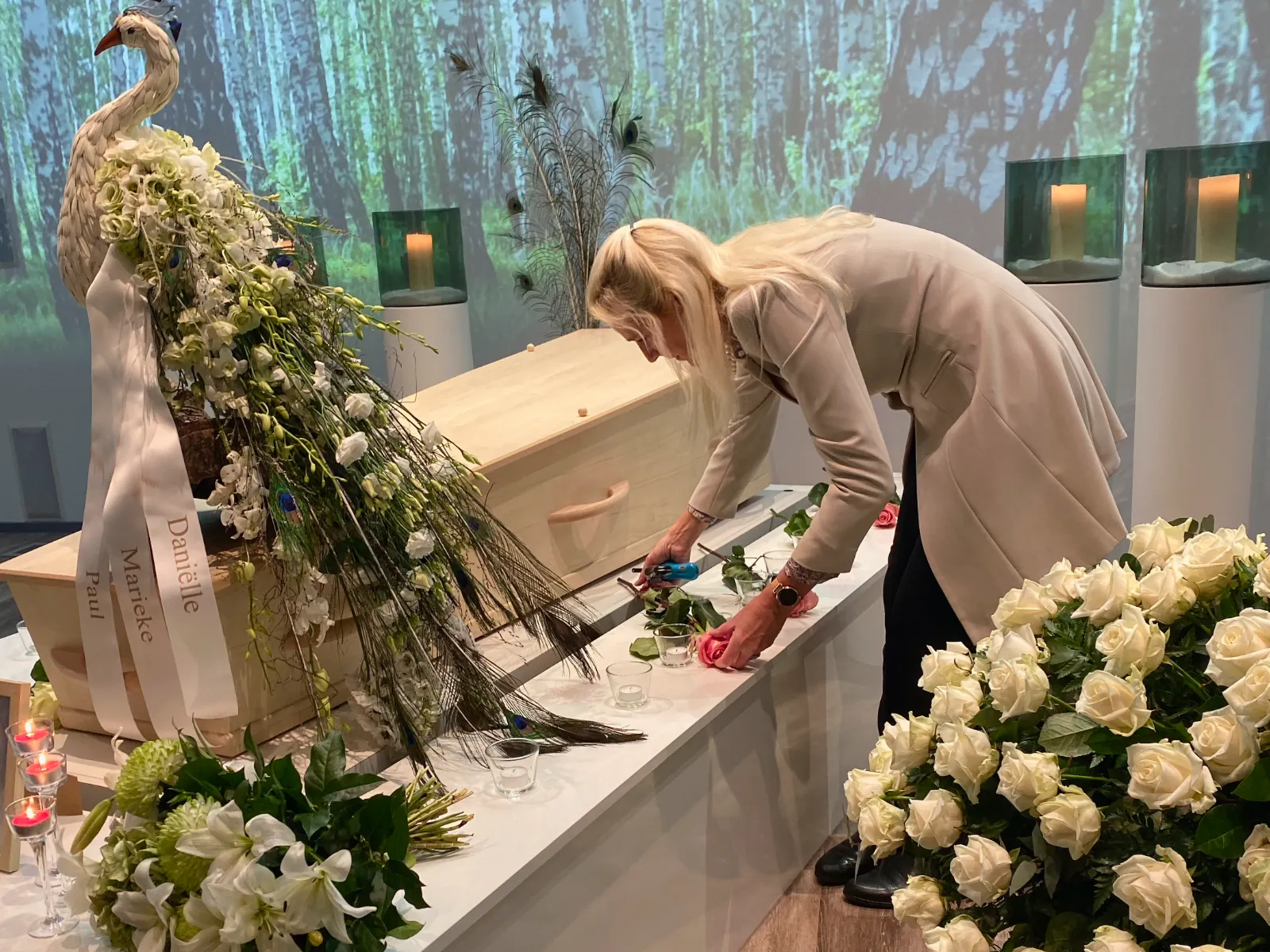 Monique Kupras van Infinity Uitvaartzorg verzorgt bloemen bij een persoonlijke uitvaart in Zoetermeer, met een bloemstuk en witte pauw als symbool van zorg en liefdevolle aandacht.