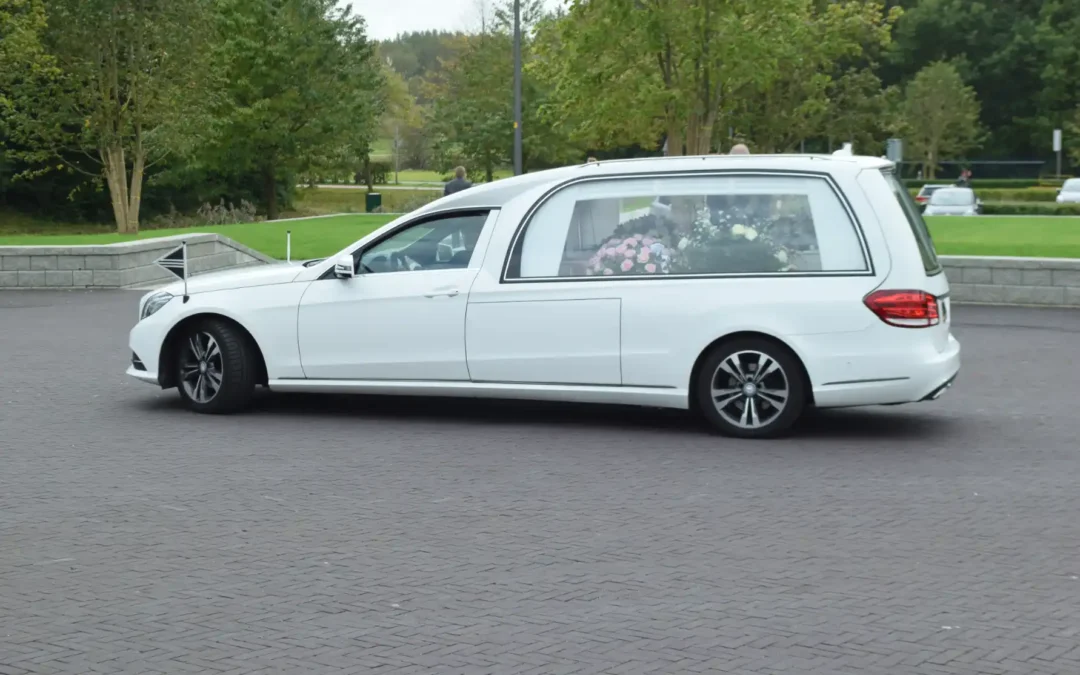 Witte Mercedes rouwauto met bloemen